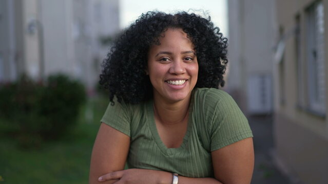One happy young black latina woman smiling at camera. A Brazilian African American female person with curly hair closeup face
