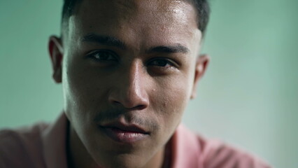 Portrait of a hispanic young man closeup face with serious expression looking at camera. One young Brazilian South American person