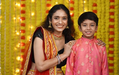 Happy young woman and son celebrating diwali holding plate of diyas,gift boxes