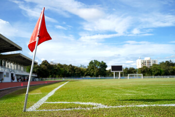 Closeup red flag in a football ground corner with bright blue sky.