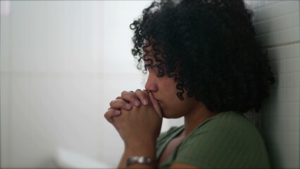 One Brazilian young woman in prayer during difficult times. A South American black latina adult...