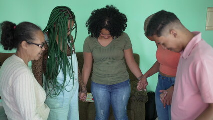 Group of hispanic family praying at home holding hands together. A latin South American friends in prayer