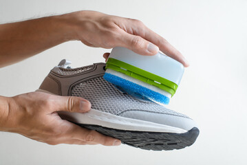 Shoe care, sneaker cleaning. Close-up of wiping shoes using a cleaning liquid with a sponge