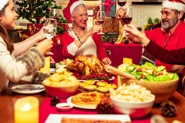 Three generation family celebration for Christmas eve. People toasting red wine glass having fun at Christmas supper reunion.