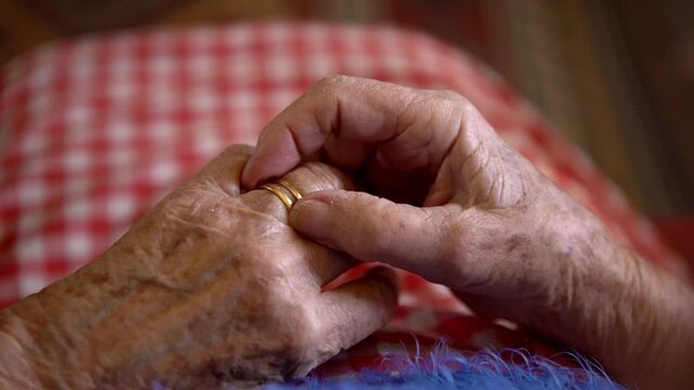 Close up elderly hands of a widowed old woman holding rings. Caucasian grandma sitting at home. Wrinkled hands of the 93th years old grandmother