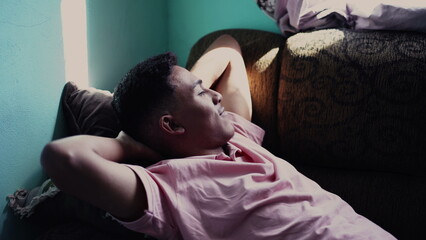 Restful hispanic person lying on couch relaxing. One South American person resting at home