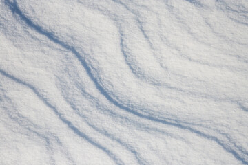 Fototapeta premium Beautiful winter background with snowy ground. Natural snow texture. Wind sculpted patterns on snow surface.