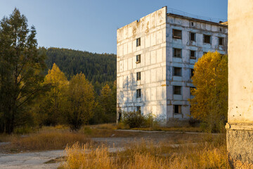 An abandoned residential building in a northern urban-type settlement in Siberia. Empty street. The problem of population decline in the Far North of Russia. Autumn season. Magadan region, Russia.