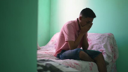 One young hispanic man in distress receiving bad news on cellphone device sitting alone in room...