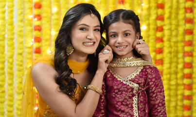 Happy young woman and daughter celebrating diwali holding gift boxes 