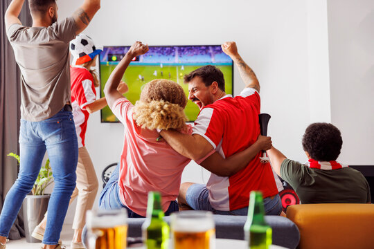 Friends cheering while watching football on TV