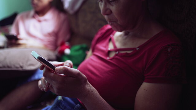 One Senior Black Hispanic Woman Using Phone At Home Looking At Device Screen