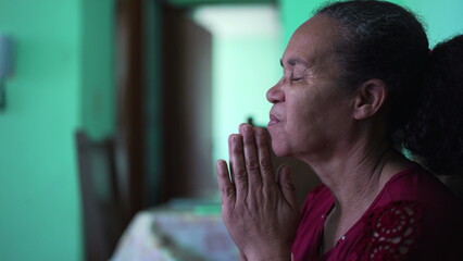 Fototapeta na wymiar Mature senior woman praying to God at home. An older latin person having HOPE and FAITH