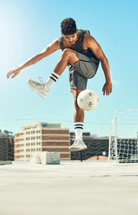 Soccer, skill and man athlete training with a ball for a game or exercise on rooftop in the city....
