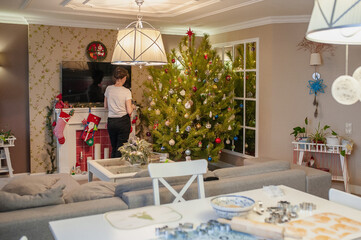 A woman is cleaning in a Christmas interior with a Christmas tree and a fireplace