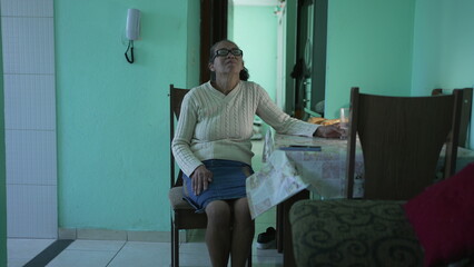 A thoughtful Senior black woman sitting a home alone. A pensive hispanic south american elderly person in living room