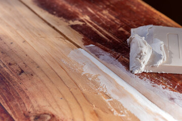 Sealing cracks in old garden table with acrylic putty. Concept repair of old wooden furniture,...