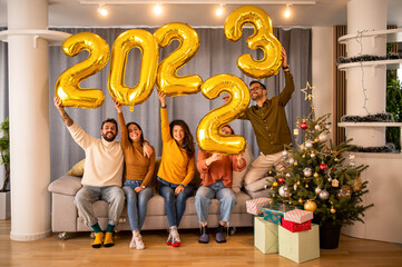 Group of young beautiful people in casual clothing carrying gold colored numbers and smiling....