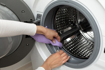 The concept of cleaning the details of a washing white machine, a stainless steel drum inside,...