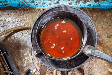 Pouring used cooking oil from frying pan in kitchen.