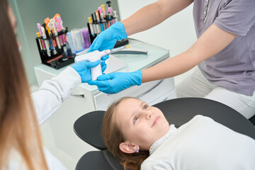 Dental staff preparing preteen girl for local anesthesia