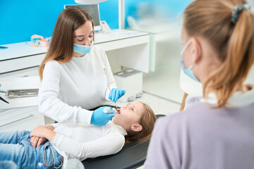 Fototapeta premium Pediatric dentist administering anesthesia to preteen girl