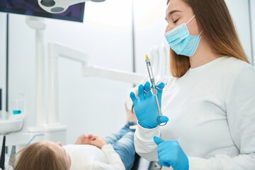 Pediatric dentist preparing to administer local anesthetic injection to patient