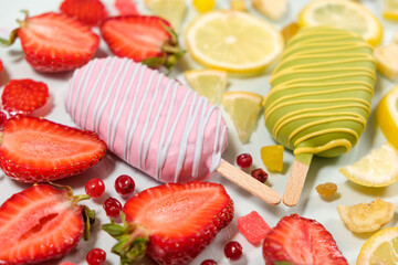 Two ice creams on a sticks - strawberry and lemon on a white background. Summer fruit desserts.