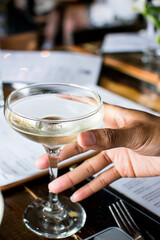 Fototapeta na wymiar Black woman hand holding a coupe cocktail glass at a restaurant 
