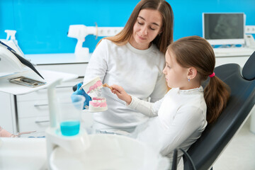 Little patient practicing tooth-brushing technique in dentist office