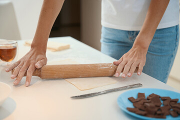 Woman rolling out sheet of dough using a rolling pin
