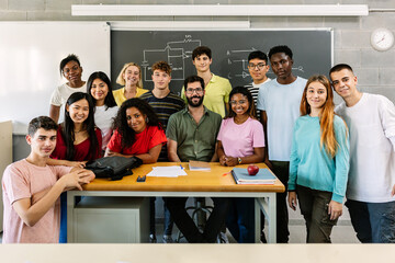 Large group portrait of millennial diverse students with male teacher smiling at camera standing...