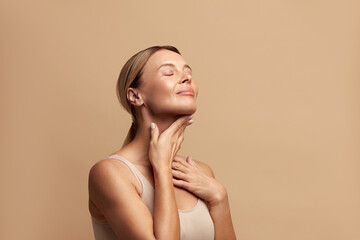 Smiling Woman Touching Neck. Waist up Portrait of Attractive Woman Touching her Skin and Smiling with Closed Eyes. Woman Appearance and skin Care Concept  - obrazy, fototapety, plakaty