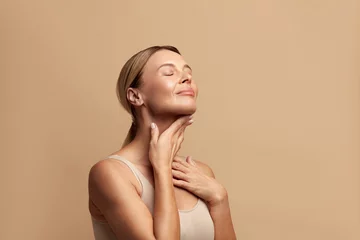 Smiling Woman Touching Neck. Waist up Portrait of Attractive Woman Touching her Skin and Smiling with Closed Eyes. Woman Appearance and skin Care Concept  © puhhha