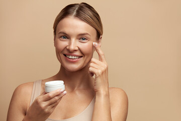 Beauty Woman Applying Face Cream. Closeup Of Female Model With Fresh Skin Holding Cream Bottle In...