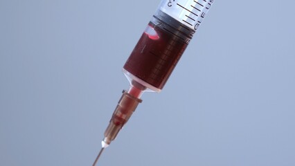 Close up of a syringe drawing blood. Syringe and blood