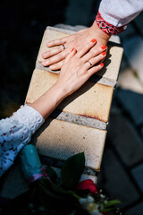 Hands of the bride and groom with rings and a wedding bouquet. Lovers in Ukrainian clothes.