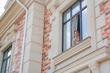 a happy bride with a glass of champagne waits for the groom at the window
