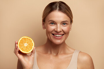 Beautiful Woman Smiling with Orange Fruit. Positive Woman with Radiant Face Skin and Orange...