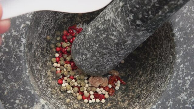 Spoon pours a variety of peppers into a mortar