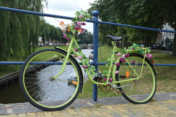 old green bicycle fixed on a bridge and decorated with flowers