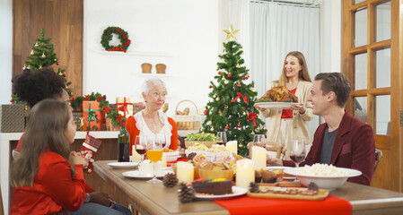 A group of multi ethnic. Portrait of Caucasian and African American black family, woman have a celebration dinner in party on Merry Christmas Eve Xmas on holiday at home or house. People lifestyle.