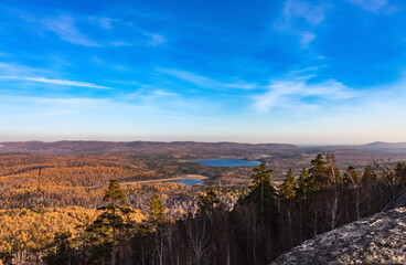Autumn landscape from the top of a mountain with a lake, trees, mountains and sky
