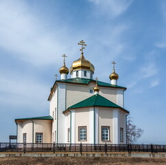 Fototapeta na wymiar The building of the Orthodox church on the background of blue sky with white clouds in spring. Russia. Ural. Aramashevo