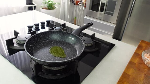 Chef cook hands pouring olive oil to wok pan on kitchen stove and roasting garlic spice. 
