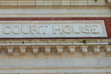 The exterior of a historical red brick judicial building with a limestone block and decorative...