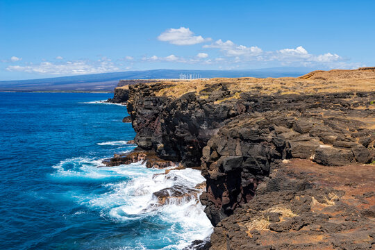 cliffs along coast at ka lae or south point hawaii southernmost point of united states and wind turbines in distance