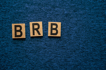 the letters b r b written in wooden blocks on a neutral blue colored background
