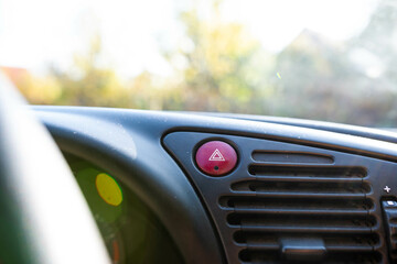 Hazard lights button in focus on old car, shallow depth of field, space for text.