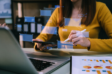 Business women using tablet with laptop and document on desk in office with virtual interface graphic icons network diagram.